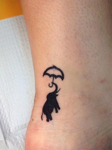 Elephant holding an umbrella tattoo